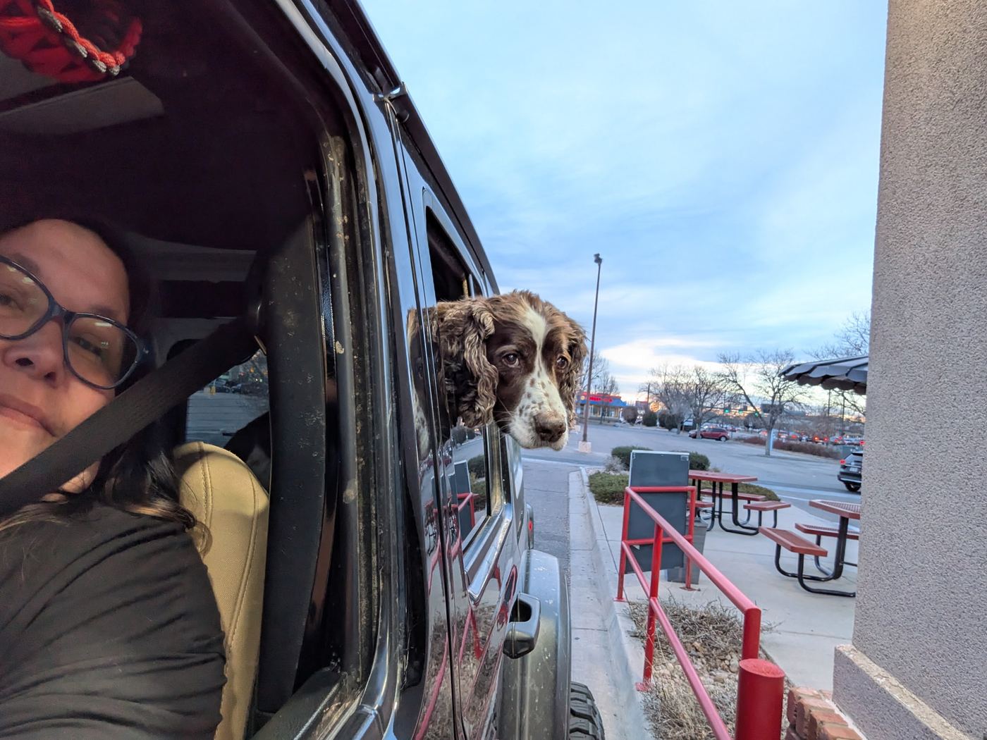Maggie with her head out the Jeep window at a drive-thru, beside a selfie from the driver’s seat.