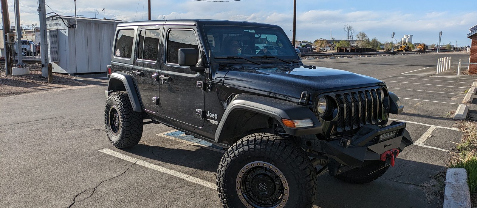 Sucia, lifted on 35s, in a parking lot by the railroad tracks in Brighton