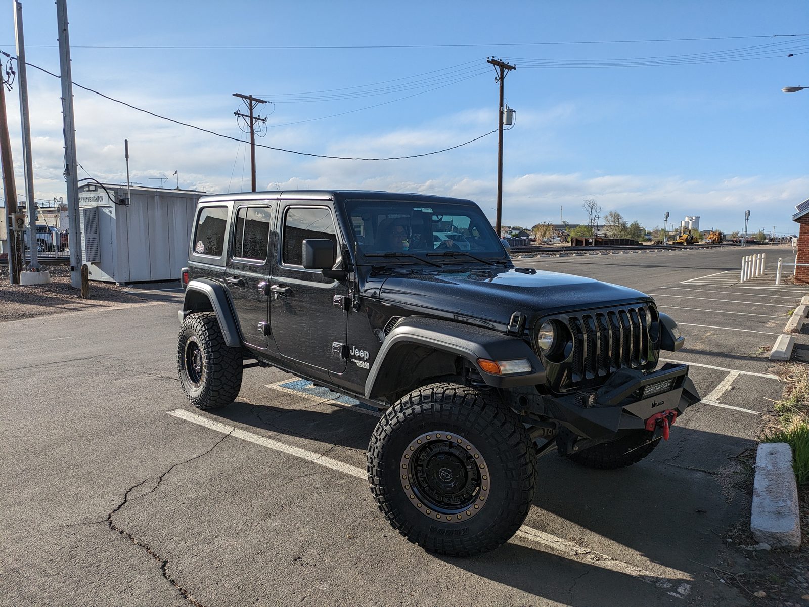 Sucia from the front corner, lifted on 35-inch Kenda tires and black beadlock wheels, in a parking lot in Brighton