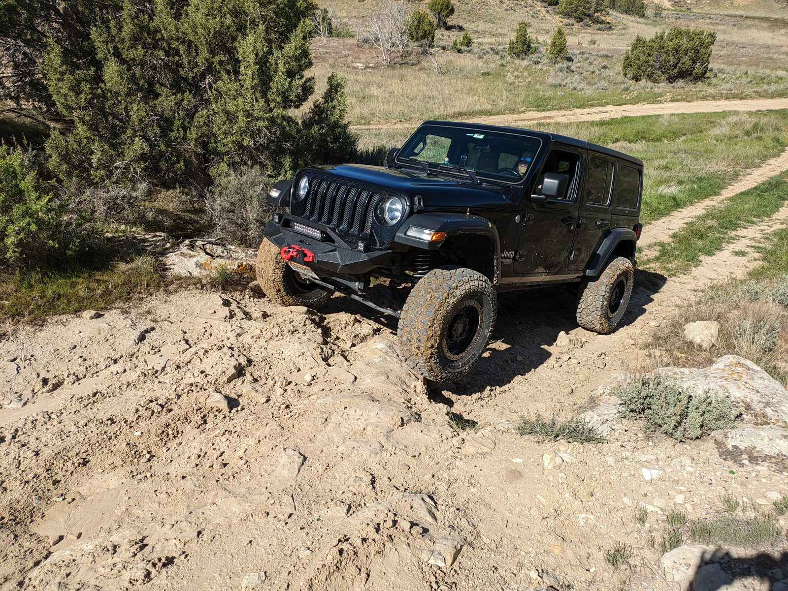 Sucia climbing over a dirt and rock ledge in the Rifle BLM area, the front passenger tire up on the rock